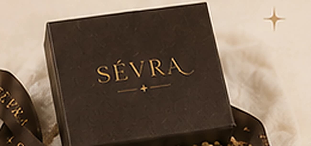 A dark chocolate SÉVRA box with a gold foil wordmark and sparkle