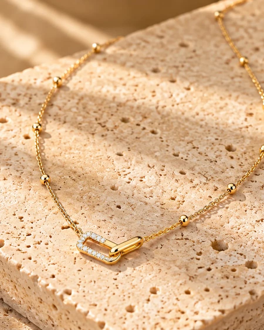 The Lumi Link Necklace photographed on a travertine block in warm daylight