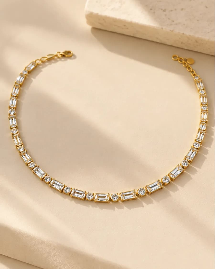 The Lumière Tennis Necklace photographed on a travertine block in warm daylight