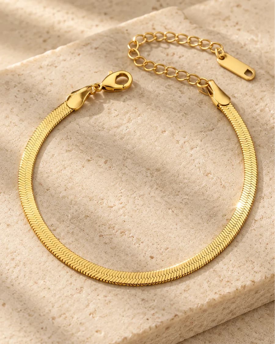 The Sleek Herringbone Bracelet photographed on a travertine block in warm daylight
