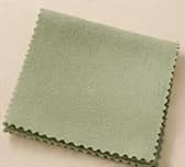 A sage green SÉVRA polishing cloth with a pinked edge