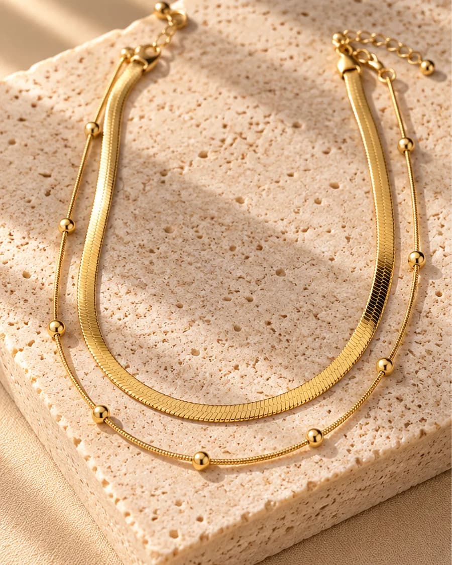 The Élan Layered Necklace photographed on a travertine block in warm daylight